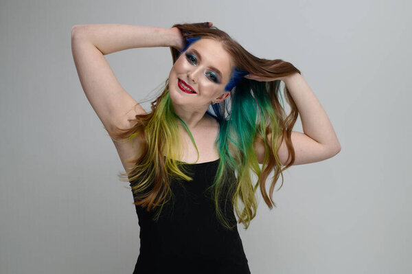 Portrait of a girl with excellent makeup with a smile with dyed hair rejoices on a white background