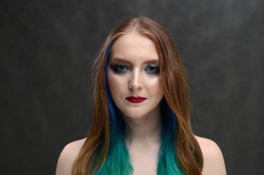 Parlak makyajlı, uzun saçlı beyaz bir kızın portresi.