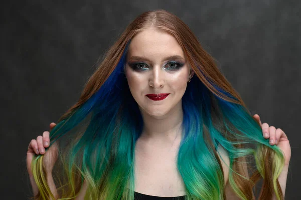 Photo of caucasian girl with dyed hair and makeup on a gray background