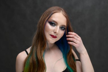 Gri arka planda boyalı saçlı bir kızın portresi.