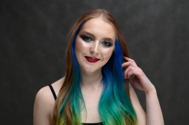 Gri arka planda uzun saçlı ve makyajlı beyaz şirin bir model portresi.