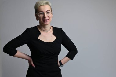 Gri arka planda gözlüklü beyaz bir kadının portresi.