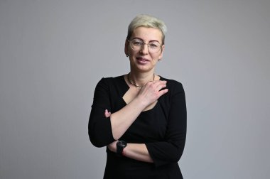 Beyaz arka planda gözlüklü beyaz sarışın bir kadının portresi.