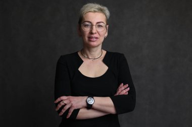 Siyah arka planda gözlüklü beyaz sarışın kadın portresi.