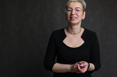 Siyah arka planda gözlüklü beyaz sarışın kadın portresi.