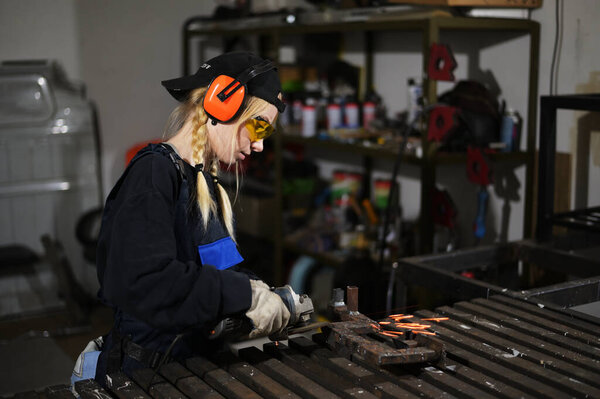 Photo of cute caucasian blonde girl with angle grinder working in glasses