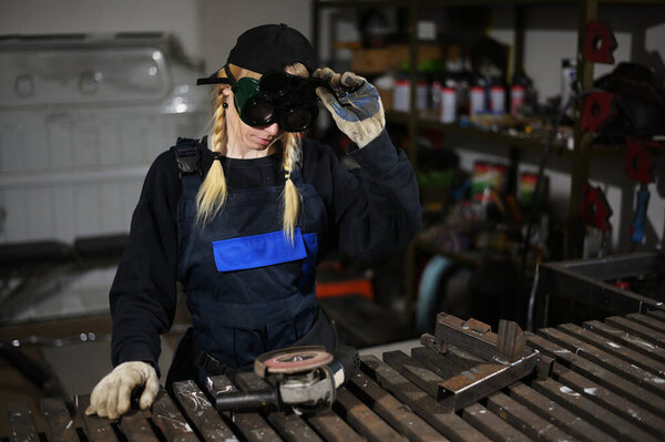 Photo of cute caucasian blonde girl with angle grinder working in glasses