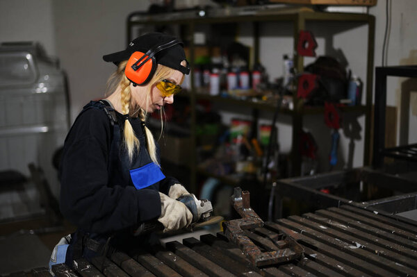 Photo of pretty woman working with angle grinder in protection