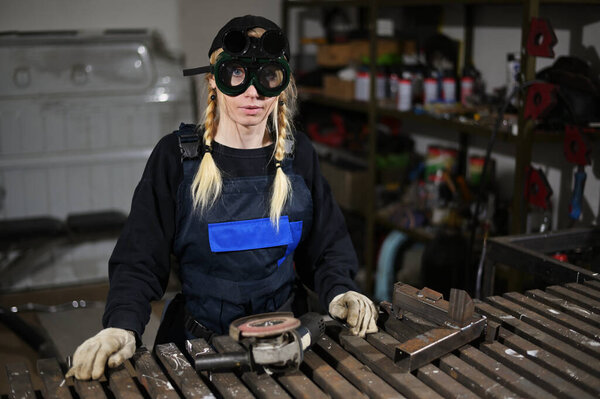 Photo of pretty woman in overalls holding an angle grinder