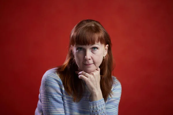 Портрет Взрослой Рыжей Женщины Смотрящей Прямо Красный Фон — стоковое фото