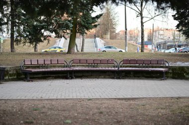 Avrupa 'da bir kentin arka planına karşı gündüz vakti bir bankın ve kaldırımın fotoğrafı