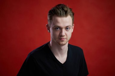 Stüdyoda kırmızı arka planda beyaz bir çocuğun yüksek çözünürlüklü fotoğrafı.