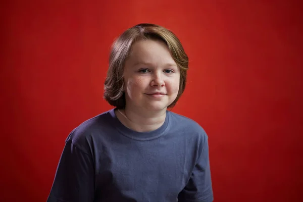照片中的一个高加索少年在红色背景上摆姿势 — 图库照片