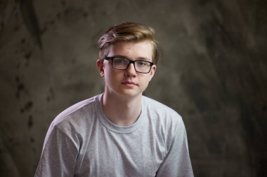 Gri arka planda gözlüklü beyaz bir gencin yüksek çözünürlüklü portresi.