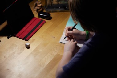 Fotoğrafçı çocuk masada ödev yapıyor.