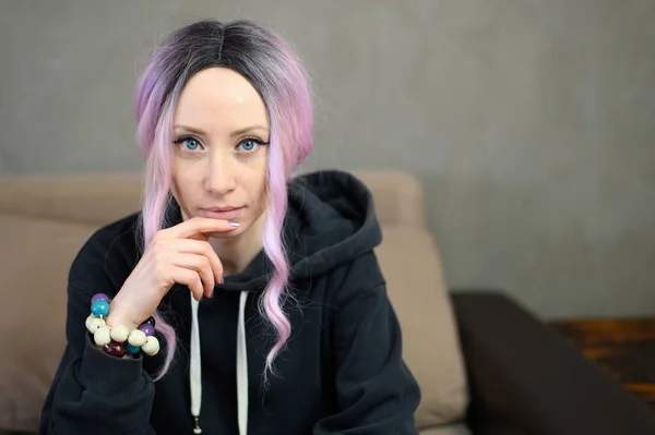 一个有着紫色头发的高加索女孩坐在沙发上看着相机摆姿势的画像 — 图库照片