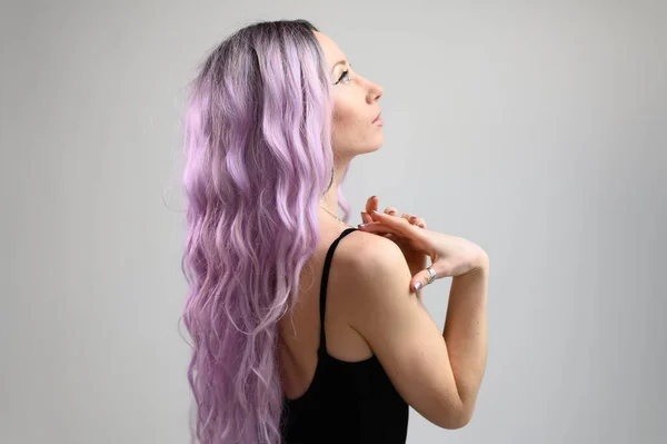 一个有着长长的紫色头发的高加索女孩的画像 她拿着白色背景的假发在镜头前摆姿势 — 图库照片