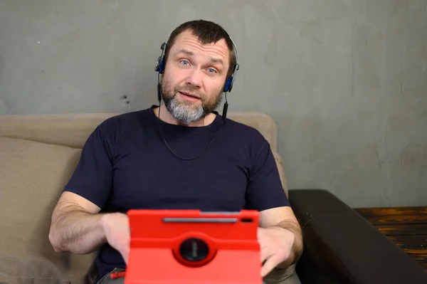 Homem Caucasiano Conversando Com Tablet Enquanto Sentado Sofá Casa — Fotografia de Stock