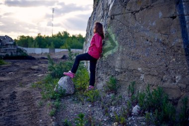 Kadın gökyüzü arka planında duvarın yanında.