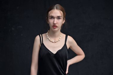 Beyaz kız cidden siyah arka planda kameraya bakıyor.