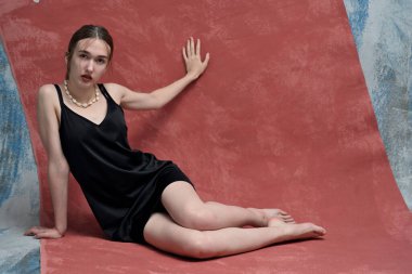 Renkli arka planda oturan genç, zayıf kadın model.