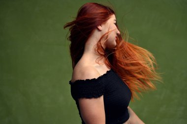 Yeşil arka planda kıvırcık saçlı kızıl saçlı beyaz bir manken. Yan görünüm