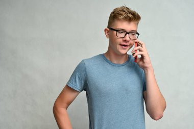 Beyaz bir arka planda telefonla konuşan, gözlüklü, yakışıklı, beyaz bir gencin portresi.