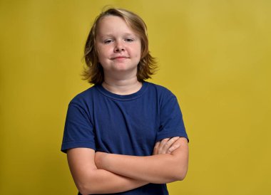 cute young guy in a blue t-shirt smiling in the studio on a yellow background