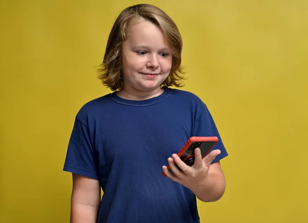 Young Guy Blue Shirt Looks Phone Yellow Background — Stock Photo, Image