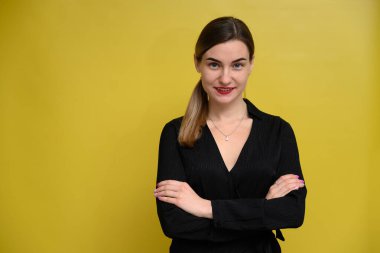 Kadın yönetici kameranın önünde gülümseyerek poz veriyor sarı arka planda duruyor. Bankacılık kavramı.