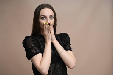 Güzel esmer kadın bej arka plandaki kameraya bakarken şaşırdı.