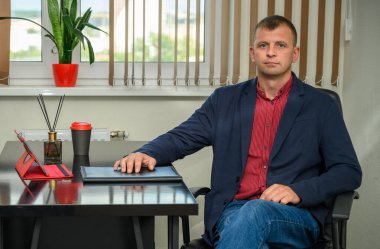 Ofisteki masanın yanında oturan ceketli bir iş adamı.