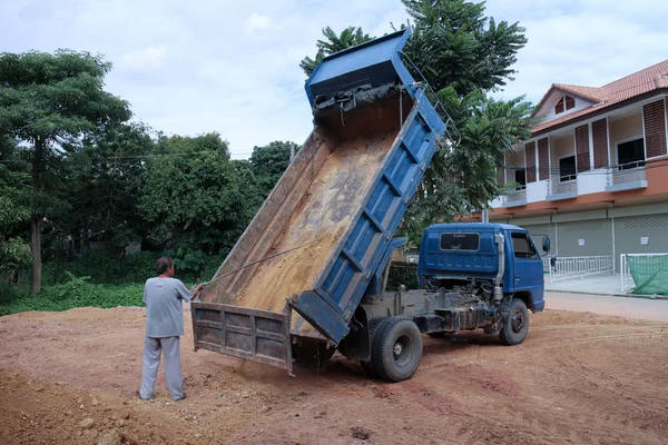 Truck driver cleaning dump truck