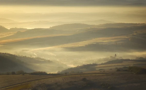 Mist en de zon stijgt boven een bergdorp — Stockfoto