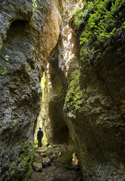 Uomo in un passaggio attraverso enormi rocce — Foto Stock