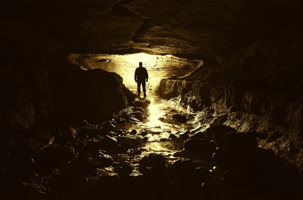 Темная пещера с силуэтом человека — стоковое фото