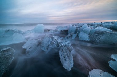 Gün batımında Jokulsarlon sahilinde siyah kumlu buz kayası. Güneydoğu İzlanda 'da elmas plajı.