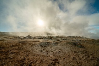 İzlanda 'daki Namafjall Hver jeotermal alanı. Duman tüten fümerolleri ve mavi bulutlu gökyüzü, seyahat geçmişi, turistik cazibesi olan şaşırtıcı kükürt vadisi manzarası.