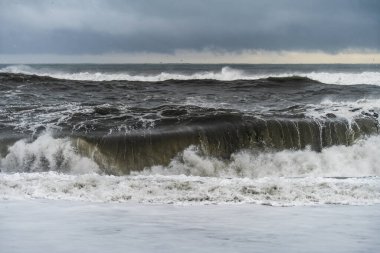 İzlanda 'nın güney kıyısındaki ünlü Reynisfjara kayaları yakınlarındaki kara volkanik sahilde şiddetli dalgalar.