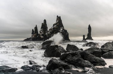 Bazalt kaya oluşumları siyah sahilde Trol ayak parmakları. Fırtınada Reynisdrangar, Vik, İzlanda