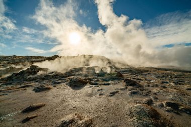 İzlanda 'daki Namafjall Hver jeotermal alanı. Duman tüten fümerolleri ve mavi bulutlu gökyüzü, seyahat geçmişi, turistik cazibesi olan şaşırtıcı kükürt vadisi manzarası.