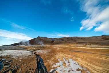 İzlanda 'daki Namafjall Hver jeotermal alanı. Duman tüten fümerolleri ve mavi bulutlu gökyüzü, seyahat geçmişi, turistik cazibesi olan şaşırtıcı kükürt vadisi manzarası.