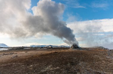 İzlanda 'daki Namafjall Hver jeotermal alanı. Duman tüten fümerolleri ve mavi bulutlu gökyüzü, seyahat geçmişi, turistik cazibesi olan şaşırtıcı kükürt vadisi manzarası.
