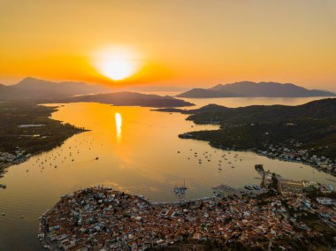 Gün batımında Poros adasındaki Kastro dağ kilisesi ve şehir havadan görünüyor. Yazın Yunanistan