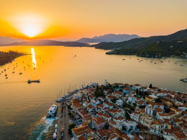 Gün batımında Poros adasındaki Kastro dağ kilisesi ve şehir havadan görünüyor. Yazın Yunanistan