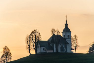 Bulutlu havada renkli bir gün batımı. Kilisenin manzarası Sv Sobota. Slovenya sonbaharda