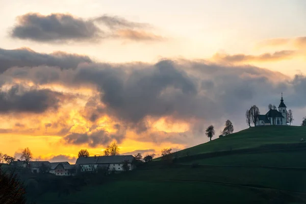 Um pôr-do-sol colorido em tempo nublado. Vista da igreja Sv Sobota. Eslovénia no Outono — Fotografia de Stock