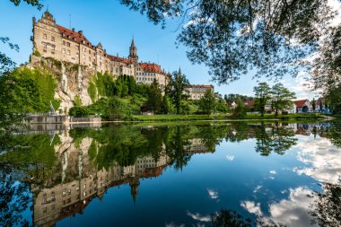 Schloss Sigmaringen 'in nefes kesici yaz manzarası sakin sulara güzel bir şekilde yansıyor, Alman mirasının özünü yakalıyor..