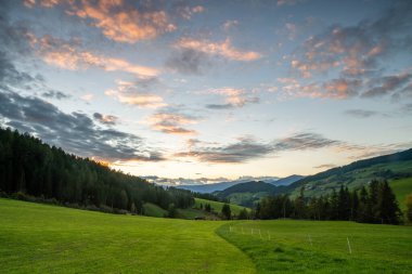 Santa Maddalena 'daki Alplerin göz kamaştırıcı güzelliğini canlı günbatımı gökyüzü ve yemyeşil.
