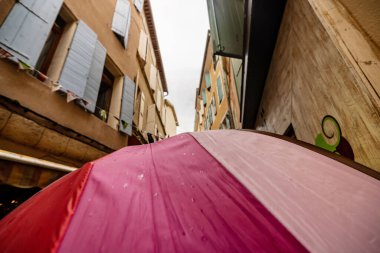 Menasque, Provence 'ın pitoresk caddelerinde yağmurlu günlerin cazibesini gösteren büyüleyici bir şemsiye manzarası..